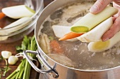 Vegetables being added to a soup chicken
