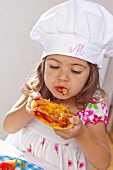 Kleines Mädchen isst Minipizza