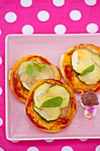 Mini pizzas topped with courgette, cheese and basil