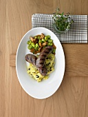 Lamb sausages with broad beans and mashed potatoes with olives