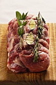 Raw rolled roast pork with rosemary, bay leaf and sage