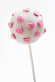 A white cake pop with pink sugar hearts