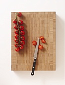 Cherry tomatoes with a knife on a chopping board
