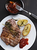 A grilled steak with potatoes, barbeque sauce and rosemary