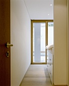 A view through an open door onto a terrace door and a cupboard under a bed