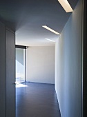 A view along a corridor into an empty room with strip ceiling lighting