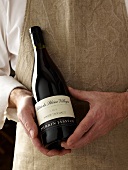 A man holding a bottle of red wine (Cote du Rhone Villages)