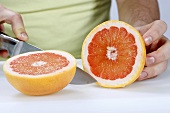 A man cutting a grapefruit in half