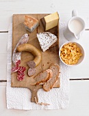 A cheese and meat platter with cornflakes and milk (seen from above)