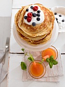 Carrot drinks and pancakes with yoghurt and berries