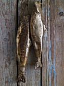 Two smoked fish hanging on a wall