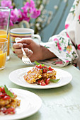 A woman in a dressing gown eating a corn and tuna cake