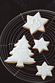 Shortbread biscuits with white icing (a Christmas tree and stars) on a wire rack