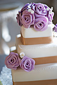 A three tier wedding cake with purple marzipan roses