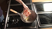 Putting prawns, garlic, chilli and herbs into wok
