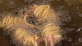 Taking deep-fried noodle-wrapped prawns out of wok