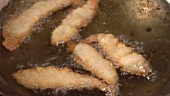 Frittierte Garnelen mit einem Schaumlöffel aus dem Fett heben