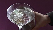 Martini aus Cocktailshaker in ein gekühlhtes Glas gießen