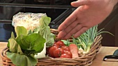 Hand showing basket of vegetables