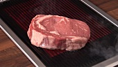 Turning beefsteak on an electric grill with tongs
