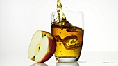 Ice cube falling into a glass of apple juice