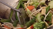 Mixing sprouts with vegetables in a wok