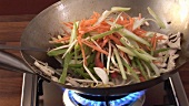 Sautéing chicken and vegetables in a wok