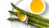Spooning melted butter over asparagus