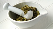 Putting cardamom pods into mortar with pestle