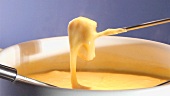 Dipping white bread into cheese fondue with fondue fork