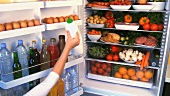 Taking a bottle of milk from a full refrigerator