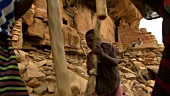 Afrikanerinnen zerkleinern Getreidekörner mit Holzstöcken