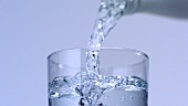 Wasser aus der Flasche in ein Glas gießen