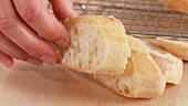 Ciabatta slices being placed on an oven rack