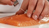 Removing the bones from a fillet of salmon with fish bone tweezers