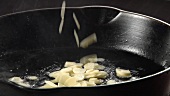 Garlic being fried in a pan of hot oil