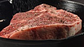 Steak in der Pfanne mit Salz bestreuen
