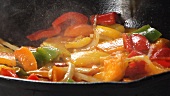 Peppers and onions being fried in a pan