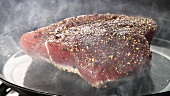 A tuna steak being fried in a pan