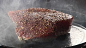 A tuna steak being turned over in a hot pan