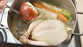 Chicken, onion and mirepoix simmering in a pot