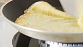 Pancakes being baked and turned in a pan