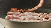 Rashers of bacon being fried in a pan (US-English Voice Over)