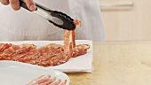 Gebratene Baconscheiben auf Küchenpapier abtropfen lassen