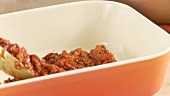 Minced meat sauce being poured into a baking dish