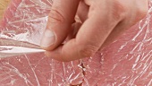 Frischhaltefolie von den flachgeklopften Kalbfleischscheiben entfernen