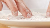 Dusting a seasoned escalope in flour