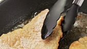 Breaded escalopes being fried in a pan