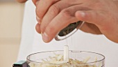 Grated cheese in a mixer being seasoned with pepper