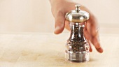 A pepper mill being picked up